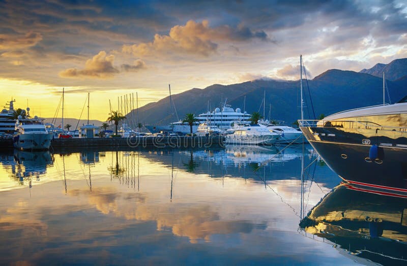 Bello paesaggio di sera con gli yacht, le nuvole dorate e le riflessioni in acqua Il Montenegro, Teodo, porticciolo Oporto Monten immagine stock Bello paesaggio di sera con gli yacht, le nuvole dorate e le riflessioni in acqua Il Montenegro, Teodo, porticciolo Oporto Monten immagine stock