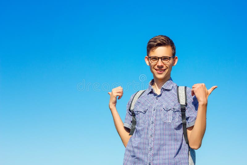 Bello ritratto di un giovane con i vetri su un fondo del cielo blu fotografia stock libera da diritti Bello ritratto di un giovane con i vetri su un fondo del cielo blu fotografia stock libera da diritti