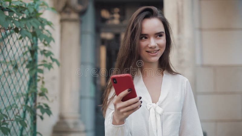 Bello Sorridente Brunette Girl che cammina in una robusta architettura della città vecchia mentre usa il suo telefono in una cust