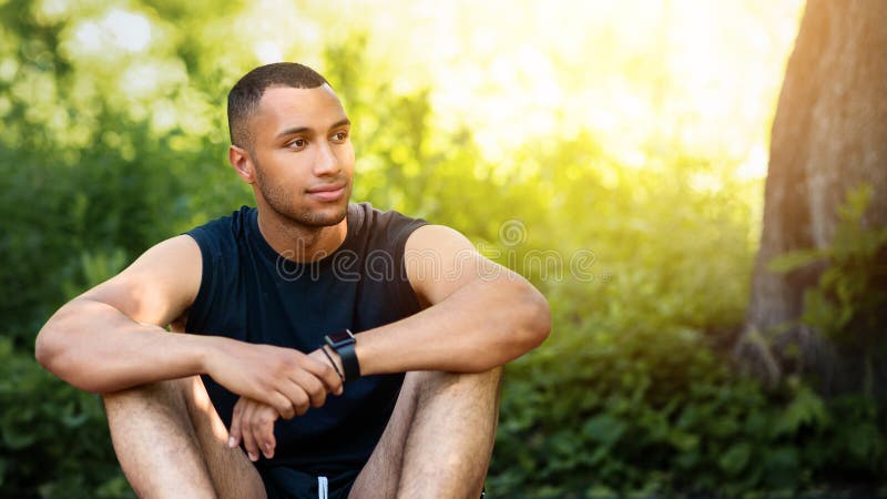 Bello sportivo afro-americano seduto per strada dopo la sua formazione a Park immagini stock libere da diritti