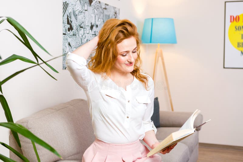 Bello studente della giovane donna con capelli rossi lunghi in libro di lettura rosa della camicia e della gonna, manuale disponi immagini stock Bello studente della giovane donna con capelli rossi lunghi in libro di lettura rosa della camicia e della gonna, manuale disponi immagini stock