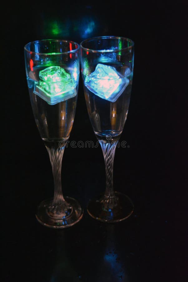Bello y brillante cubo de hielo azul flotante en una copa de champán de vidrio con una bebida. foto de archivo libre de regalías