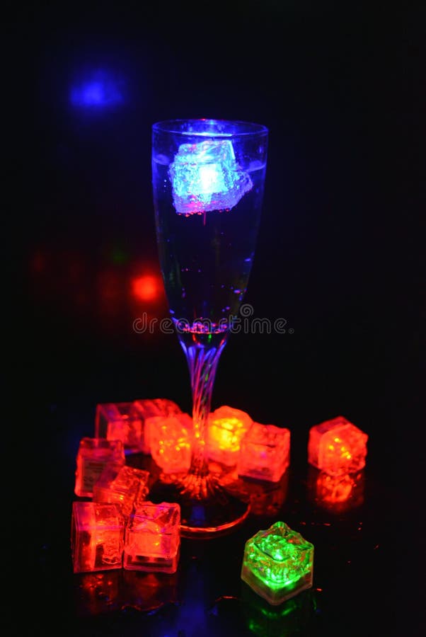 Bello y brillante cubo de hielo azul flotante en una copa de champán de vidrio con una bebida. imagen de archivo libre de regalías
