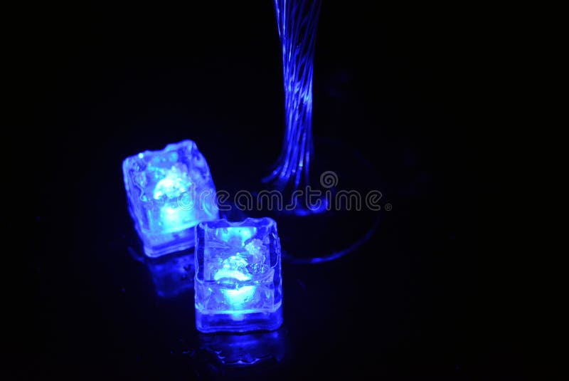 Bello y brillante cubo de hielo azul flotante en una copa de champán de vidrio con una bebida. foto de archivo libre de regalías