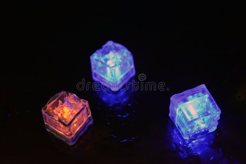 Bello y brillante cubo de hielo azul flotante en una copa de champán de vidrio con una bebida. fotos de archivo