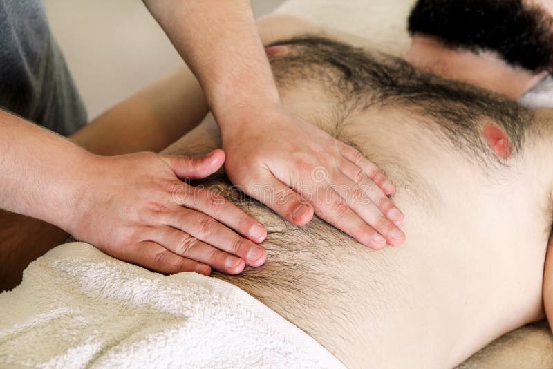 Masseur massaging mans belly.