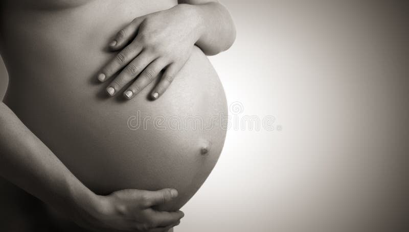 Pancia della donna incinta bianco e nero su uno sfondo scuro.