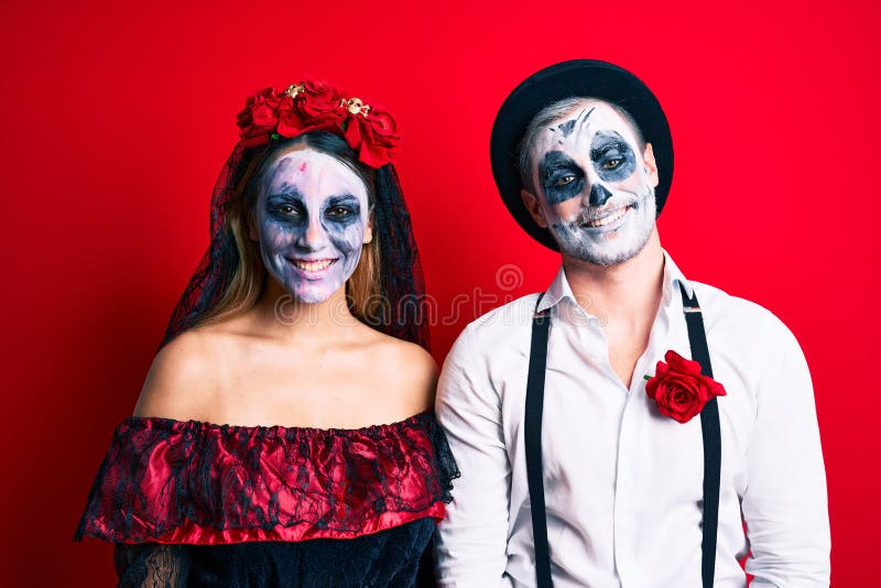 Casal vestindo fantasia de dia dos mortos sobre vermelho sorrindo fazendo  moldura com mãos e dedos com cara de feliz. conceito de criatividade e  fotografia.