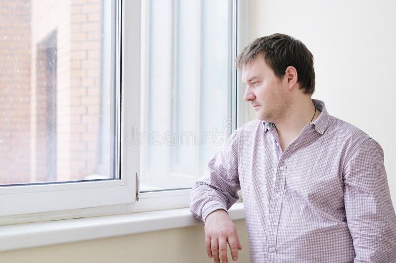 Bemannen Sie das Betrachten des Schnees in das Fenster lizenzfreie stockbilder Bemannen Sie das Betrachten des Schnees in das Fenster lizenzfreie stockbilder