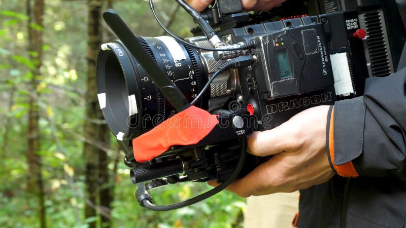 Bemannen Sie das Halten einer Kamera, die im Wald einen Film in der Waldteuren Kamera für Film filmt stockfoto Bemannen Sie das Halten einer Kamera, die im Wald einen Film in der Waldteuren Kamera für Film filmt stockfoto