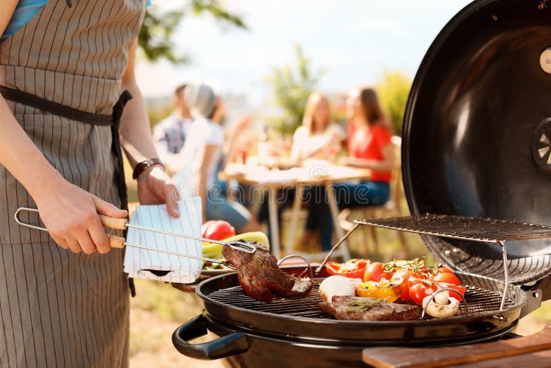 Bemannen Sie das Kochen des Fleisches und des Gemüses auf Grillgrill lizenzfreies stockbild Bemannen Sie das Kochen des Fleisches und des Gemüses auf Grillgrill lizenzfreies stockbild
