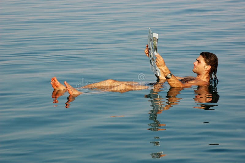 Bemannen Sie das Schwimmen in ein Totes Meer mit Zeitung lizenzfreie stockfotos Bemannen Sie das Schwimmen in ein Totes Meer mit Zeitung lizenzfreie stockfotos