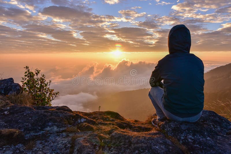 Man sitting on a mountain for watching Sunrise views alone. Man sitting on a mountain for watching Sunrise views alone.