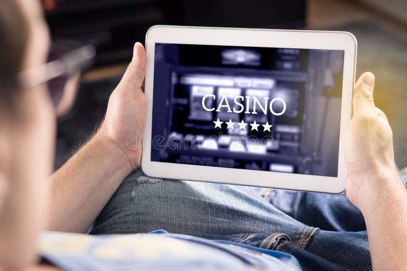 Bemannen Sie das Spielen in einem on-line-Kasino mit Tablette stockfotografie Bemannen Sie das Spielen in einem on-line-Kasino mit Tablette stockfotografie