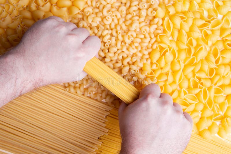 Bemannen Sie das Versuchen, Brunch von Spaghettis mit den Händen zu brechen lizenzfreie stockbilder Bemannen Sie das Versuchen, Brunch von Spaghettis mit den Händen zu brechen lizenzfreie stockbilder