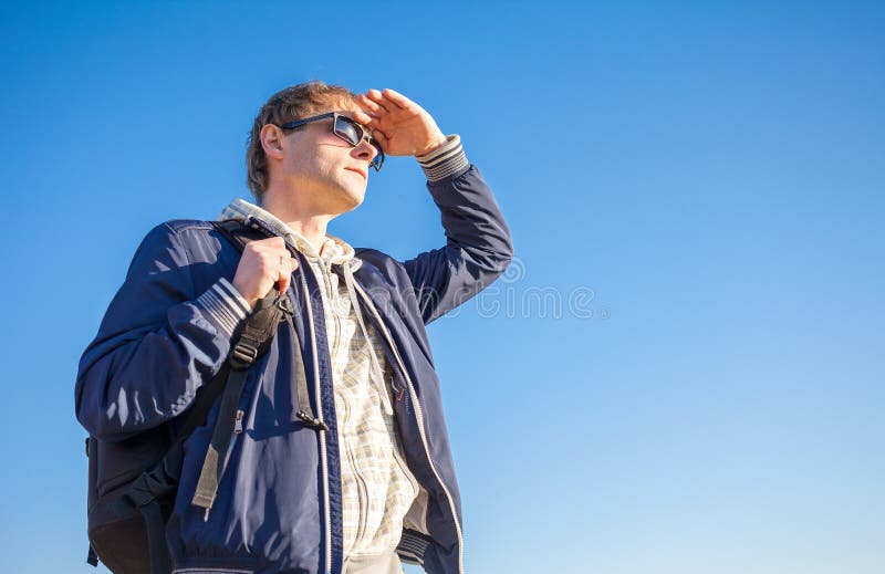 Bemannen Sie den Wanderer, der Rucksack an einem sonnigen Tag gegen einen blauen Himmel hält lizenzfreie stockbilder Bemannen Sie den Wanderer, der Rucksack an einem sonnigen Tag gegen einen blauen Himmel hält lizenzfreie stockbilder