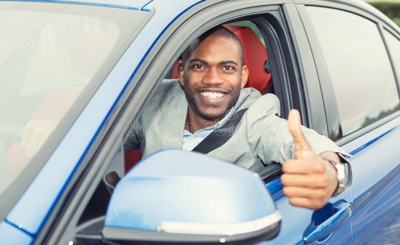 Car. Man driver happy smiling showing thumbs up coming out of blue car side window on outside parking lot background. Young man happy with his new vehicle. Positive face expression. Car. Man driver happy smiling showing thumbs up coming out of blue car side window on outside parking lot background. Young man happy with his new vehicle. Positive face expression