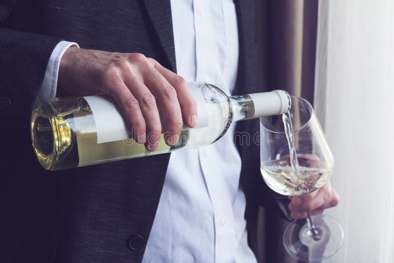 Bemannen Sie strömendes Weißwein in ein Glas lizenzfreies stockfoto Bemannen Sie strömendes Weißwein in ein Glas lizenzfreies stockfoto