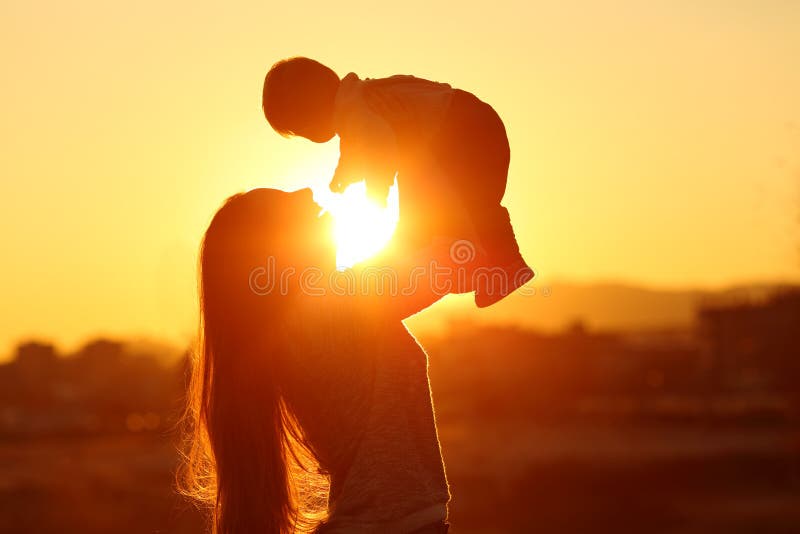 Bemuttern Sie das Aufwachsen ihres Kindersohns bei Sonnenuntergang mit der Sonne in der Mitte stockbild Bemuttern Sie das Aufwachsen ihres Kindersohns bei Sonnenuntergang mit der Sonne in der Mitte stockbild