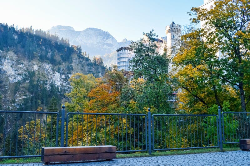 Bench and metal fence with Neuschwanstein castle on a background in the mountains in Alps