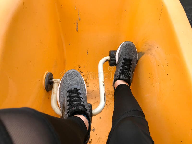 Benen in grijs de laarzenpedaal van sporttennisschoenen in een gele catamaran royalty-vrije stock afbeeldingen Benen in grijs de laarzenpedaal van sporttennisschoenen in een gele catamaran royalty-vrije stock afbeeldingen