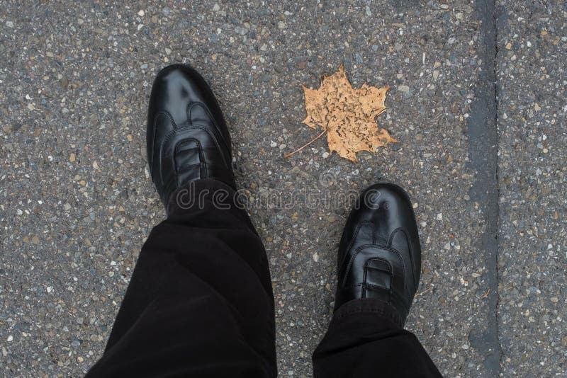 Benen met schoenen een droog esdoornblad