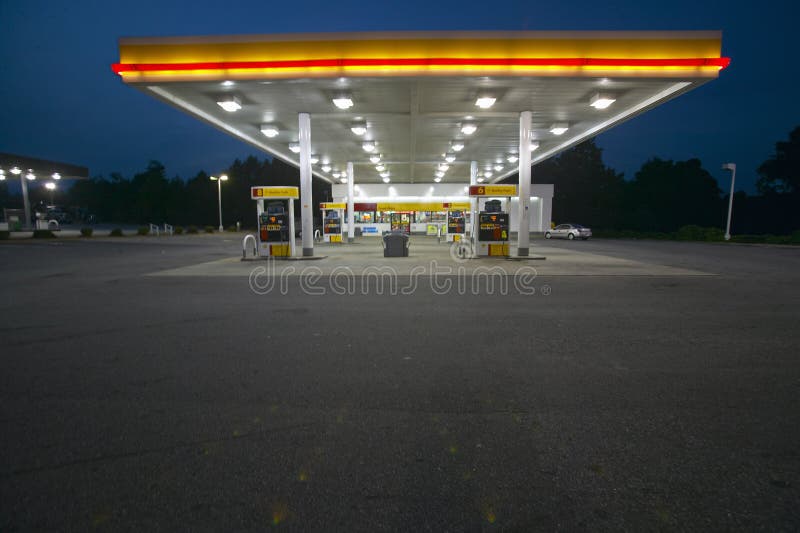 Benzynowa stacja z światłami na i halą targową przy półmrokiem w Środkowych dziąsłach