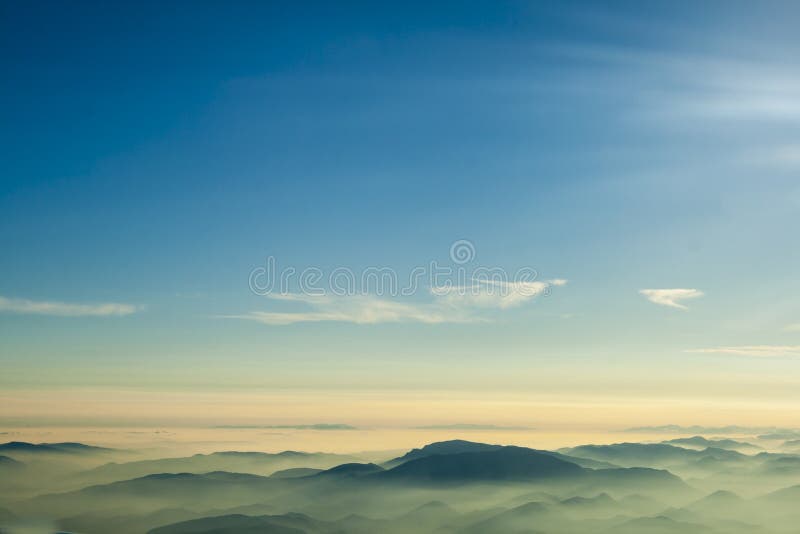Berg fördunklar blå himmel och dimma som fotograferas från på bergstoppet arkivbilder