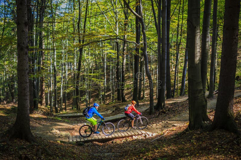 Berg som cyklar kvinnor och manridning på cyklar på solnedgångberget royaltyfria bilder Berg som cyklar kvinnor och manridning på cyklar på solnedgångberget royaltyfria bilder