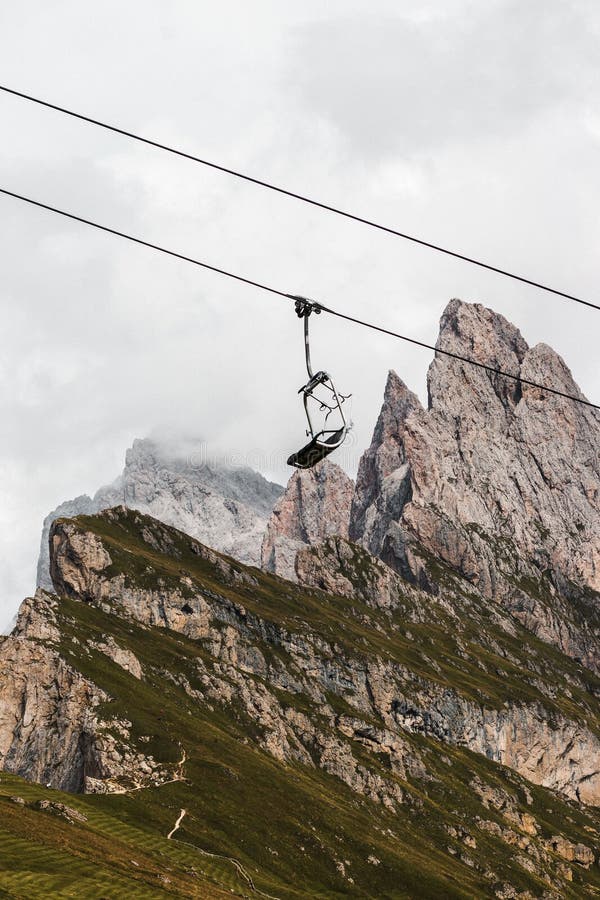 A mountain lift chair suspended on wires above a lush valley. A mountain lift chair suspended on wires above a lush valley