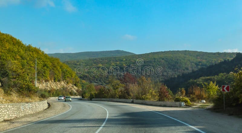 Bergväg som är slingrande mellan städer av Krim Sydkust av Crimea solig höstdag med blå himmel fotografering för bildbyråer Bergväg som är slingrande mellan städer av Krim Sydkust av Crimea solig höstdag med blå himmel fotografering för bildbyråer