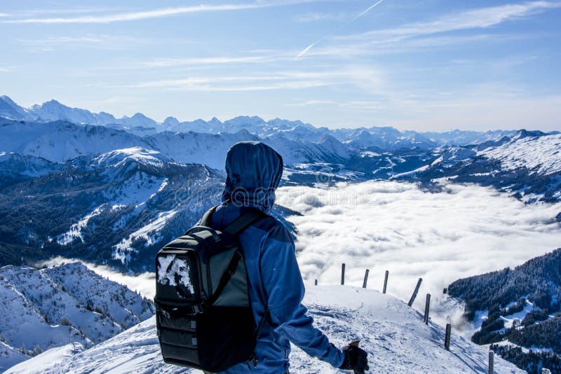 bergwandelaar in de winter door de afstand op de top van de sneeuwberg te bekijken de wolken in de vallei over het hoofd zien