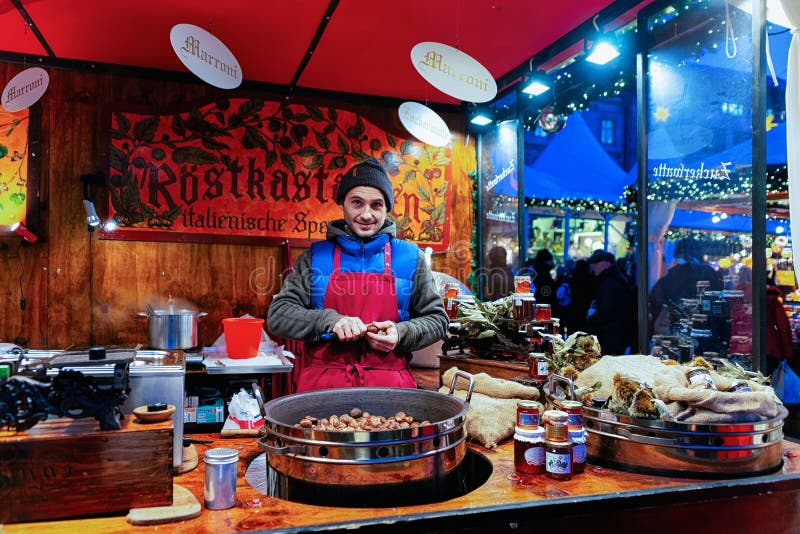 Berlin, Deutschland - 8. Dezember 2017: Mann, der Kastanien am Weihnachtsmarkt bei Gendarmenmarkt im Winter Berlin, Deutschland v lizenzfreie stockbilder Berlin, Deutschland - 8. Dezember 2017: Mann, der Kastanien am Weihnachtsmarkt bei Gendarmenmarkt im Winter Berlin, Deutschland v lizenzfreie stockbilder