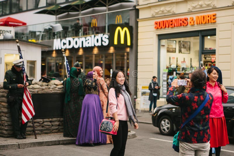 Berlin, October 1, 2017: Asian tourists are photographed next to a famous city attraction called Chekpoint Charlie royalty free stock images Berlin, October 1, 2017: Asian tourists are photographed next to a famous city attraction called Chekpoint Charlie royalty free stock images