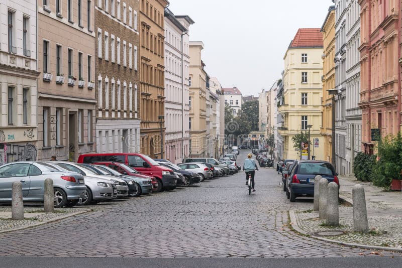 BERLIN - OKTOBER 18, 2016: En flicka på en cykel rider ner en härlig gata fotografering för bildbyråer BERLIN - OKTOBER 18, 2016: En flicka på en cykel rider ner en härlig gata fotografering för bildbyråer