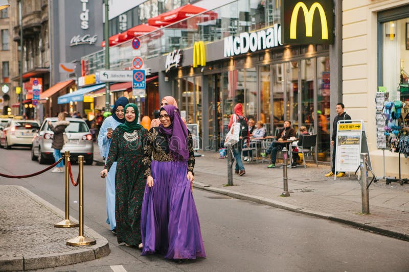 Berlin Oktober 1, 2017: Grupp av positiva kvinnor - arabiska flyktingar i medborgaredräkter med dyrt gå för telefon arkivbilder Berlin Oktober 1, 2017: Grupp av positiva kvinnor - arabiska flyktingar i medborgaredräkter med dyrt gå för telefon arkivbilder