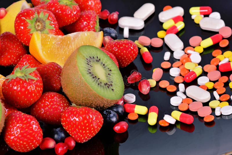 Berries, fruits, vitamins and nutritional supplements on a black background