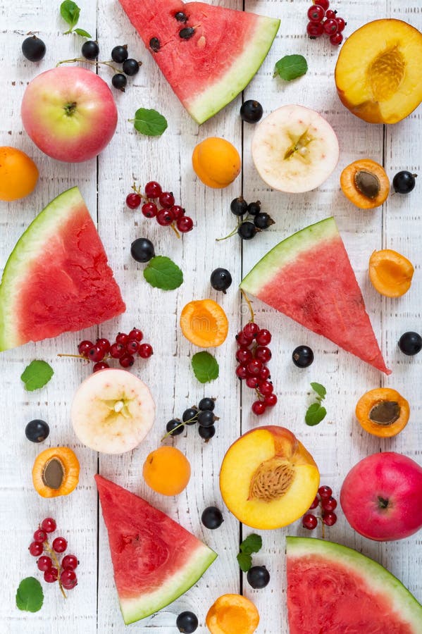 Berry background. Many summer fruits and berries are scattered on a white wooden background