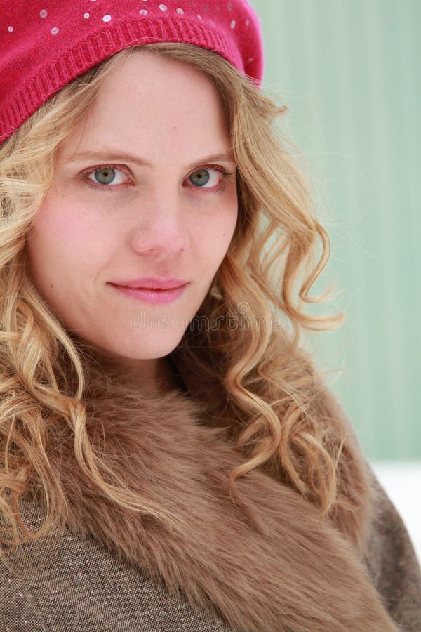 A beautiful young woman with a subtle smile on a snowy day with a building in background. A beautiful young woman with a subtle smile on a snowy day with a building in background.