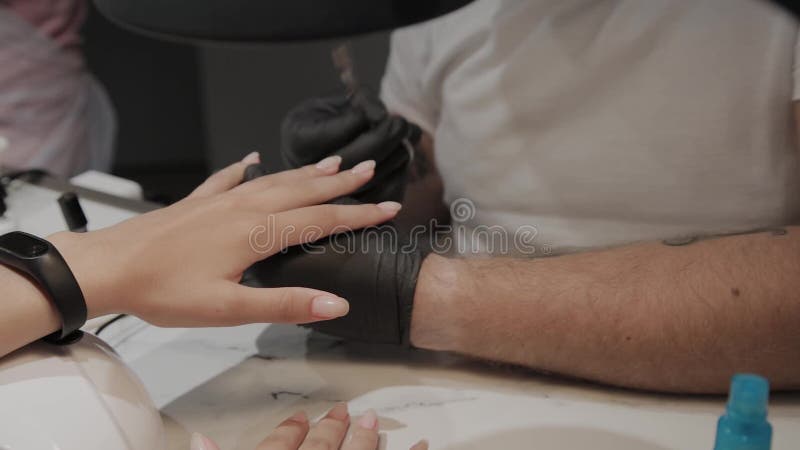 Berufsmaniküristmann lackiert die Nägel eines Mädchens