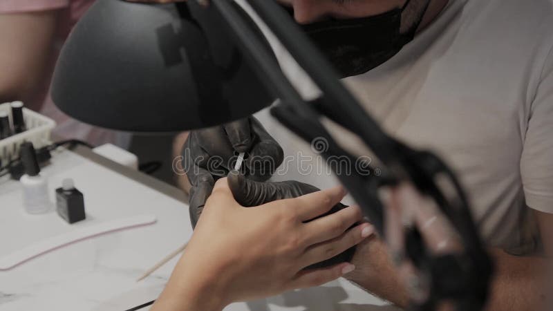 Berufsmaniküristmann lackiert die Nägel eines Mädchens
