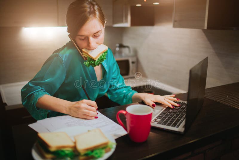 Beschäftigte Frau, die, trinkender Kaffee, sprechend am Telefon isst und gleichzeitig arbeiten an einem Laptop Geschäftsfrauhande