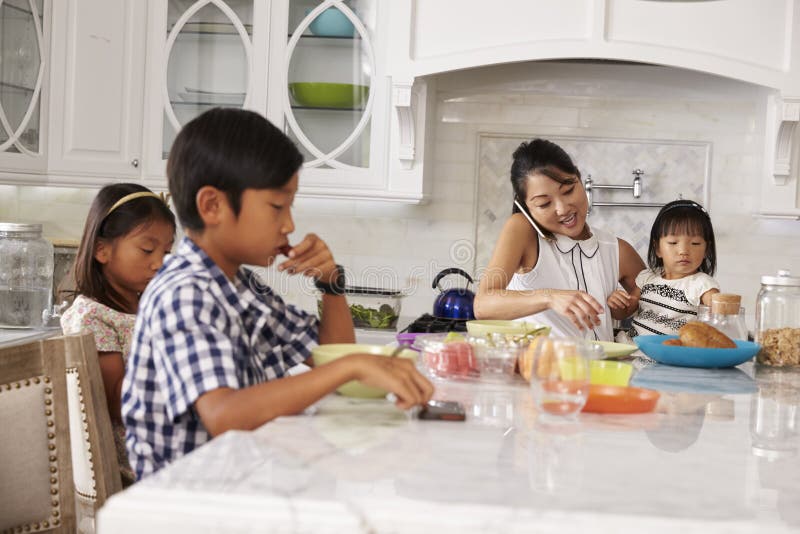 Beschäftigte Mutter-organisierende Kinder am Frühstück in der Küche
