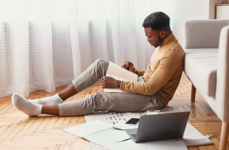 Beschäftigter Student Studying Taking Notes, das auf dem Boden Innen sitzt lizenzfreie stockfotografie