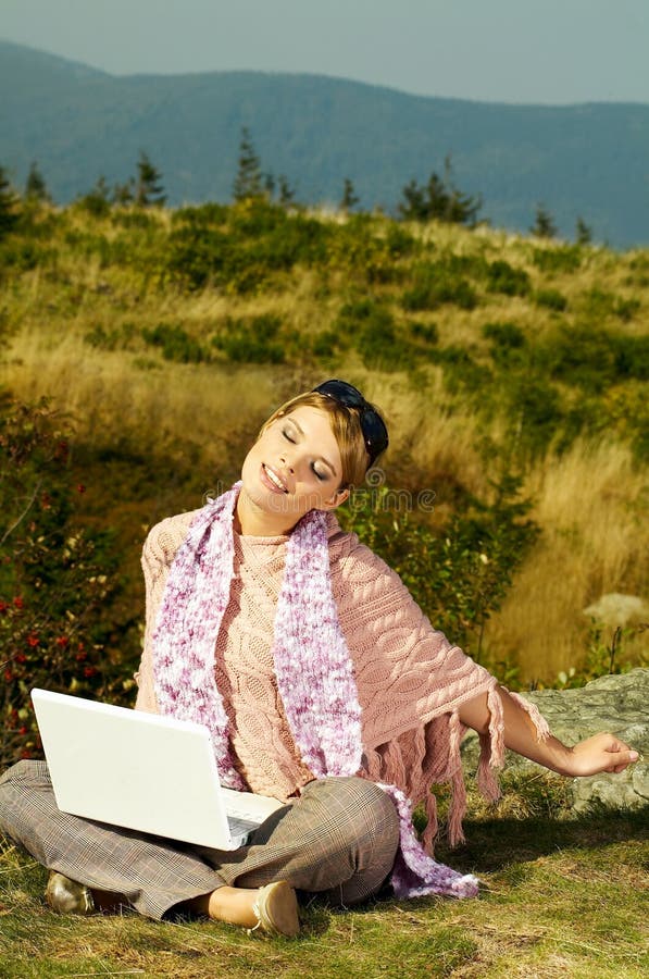 Young business woman relaxing, working on laptop computer on meadow. Young business woman relaxing, working on laptop computer on meadow