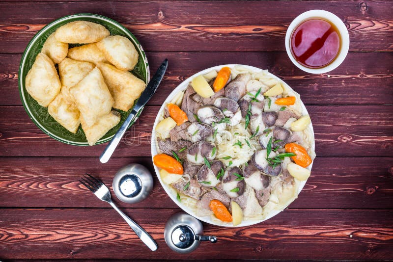 Beshbarmak dish with baursak - traditional Kazakh Asia food and national bread. Noodles with lamb and onion close-up on