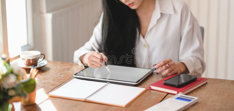 Beskjutning av en ung, vacker affärskvinna som arbetar med sitt projekt med en tablett på ett bekvämt kontor royaltyfri foto