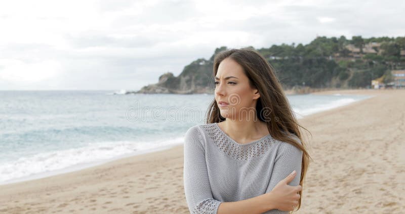 Besorgte Frau, die allein auf den Strand geht