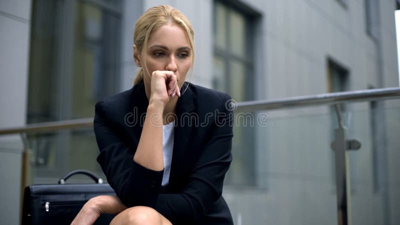 Besorgte Frau, die auf der Bank, besorgt über Entlassung von der Arbeit, Krise sitzt