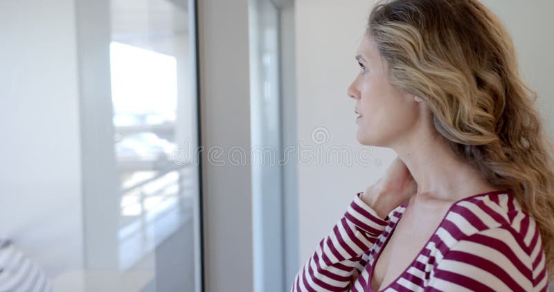 Besorgte kaukasische Mutter, die aus dem Fenster schaut, in Zeitlupe